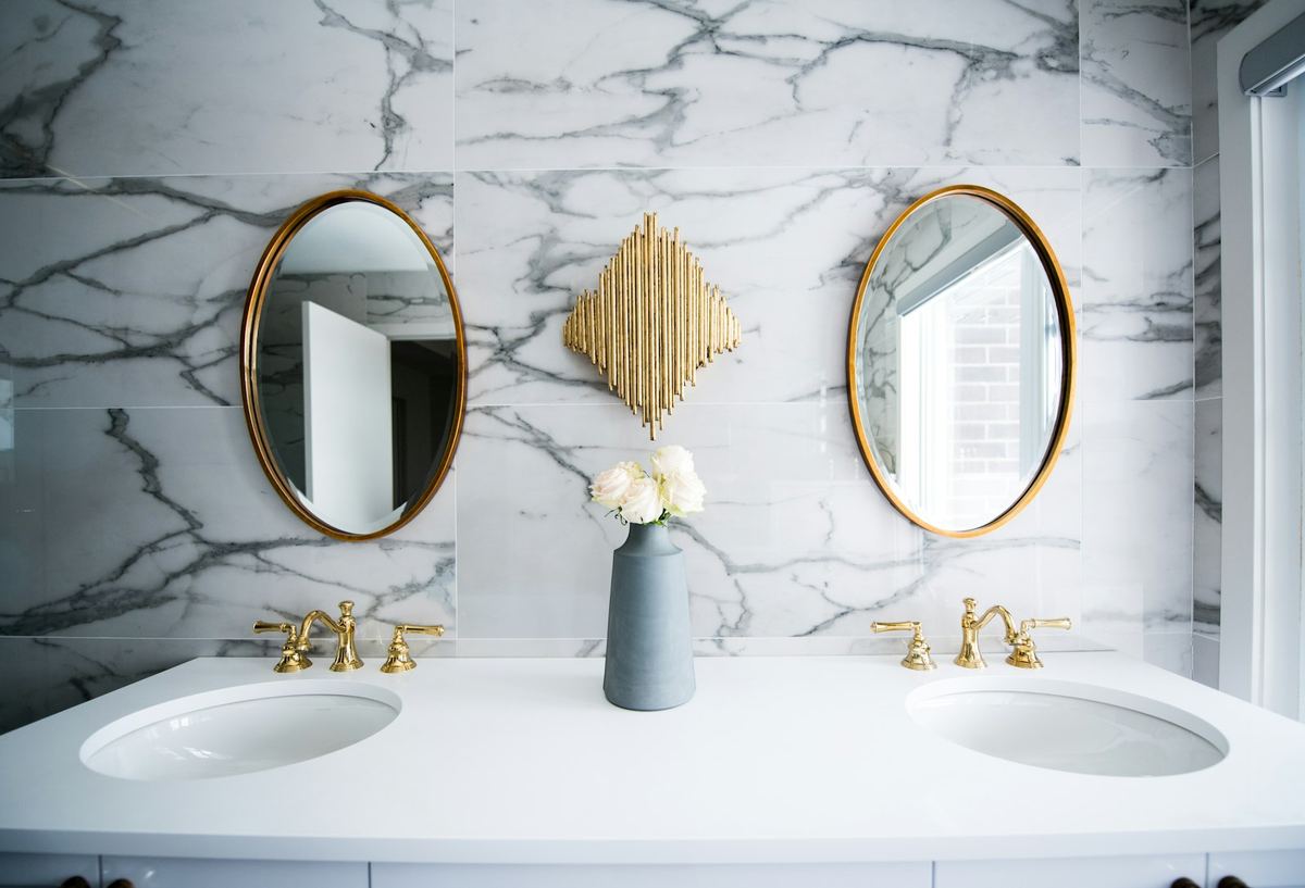 Elegantes Bad mit Marmor-Waschtisch und goldenen Armaturen